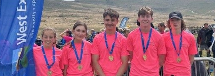 West Exe Team stood with flags either side of them at the finish of the Ten Tors